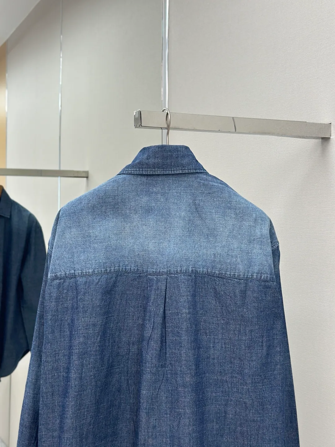 P430 Loewe Anagram Gradient Embroidered Pocket Shirt Made of custom-made high-quality cotton chambray fabric, with a unique washed gradient blue as the main tone, from dark to light and from thick to light. The chest patch pocket is decorated with Loewe Anagram embroidery as its soul, engraved with LOEWE-style casual elegance, and the natural and smooth lines show the casualness.  Imported embroidery machines are used, and advanced computer control systems and precision mechanical components are used to realize Loewe embroidery operations.  The gradient dynamic spray dyeing process uses specialized spray dyeing equipment to accurately spray dye onto the surface of the fabric in the form of mist (by accurately controlling the different dimensions of the spray of the spray dyeing equipment, combined with the movement speed and direction during the dyeing process) to present a smooth and natural transition effect of color. The butterfly rhyme pinch pleating body dart technology is inspired by the beautiful shape of butterflies, and uses precise pinch pleating techniques to create a flexible pleat effect like butterfly wings on the garment, making the garment fit more closely to the body.  size:44.46.48.50